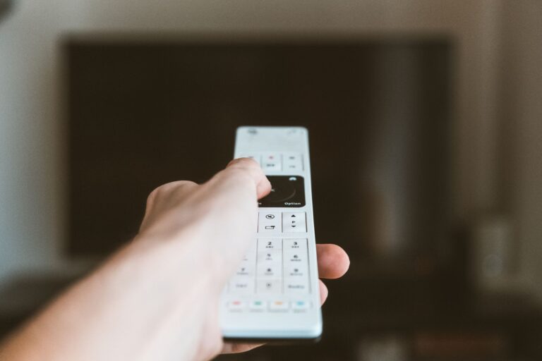 Hand pointing a remote control at a TV