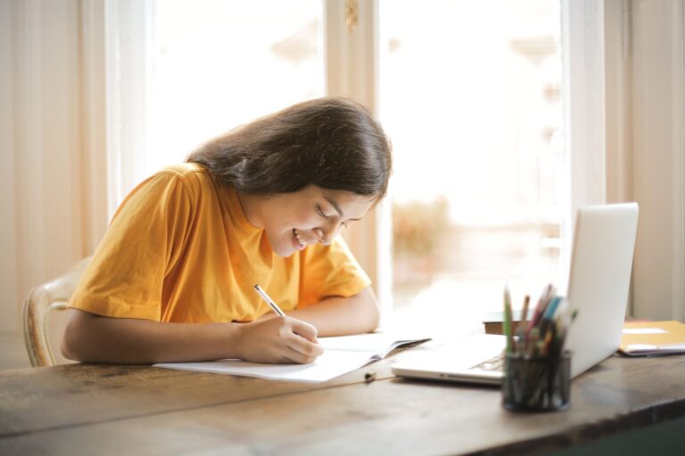 Student studying at a table with a laptop