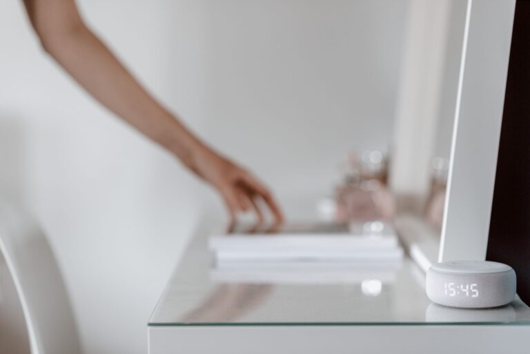 Smart speaker with a clock display on a bedside table